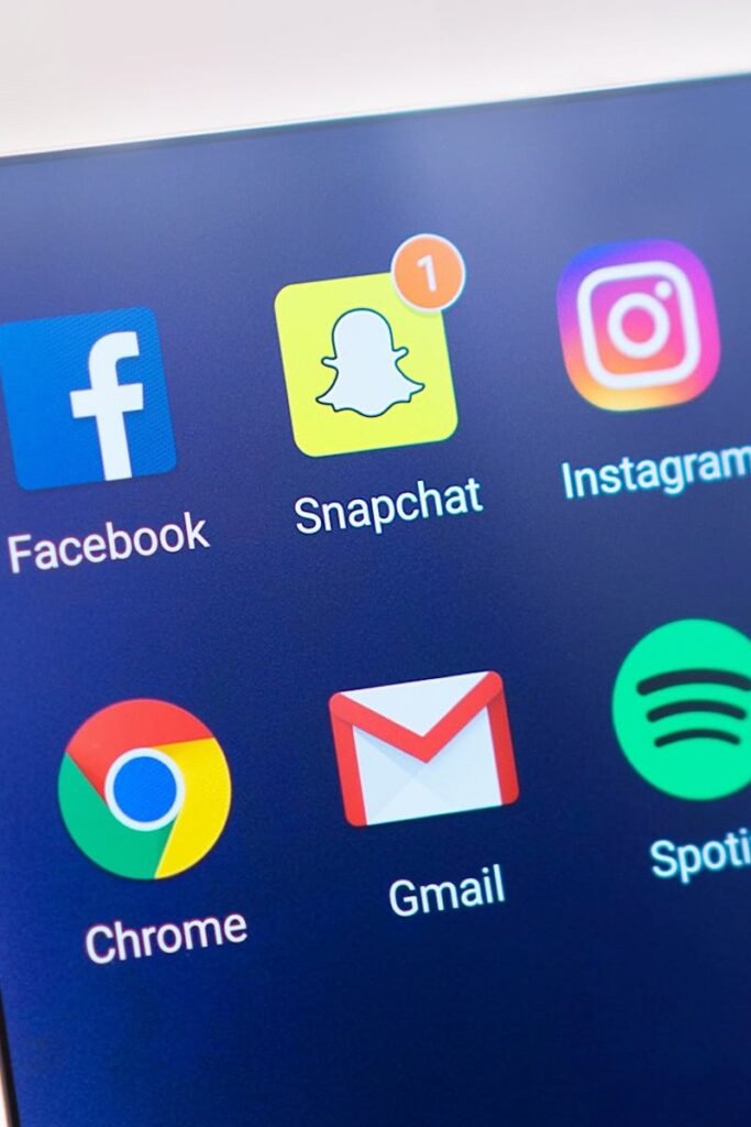 A person's hand holding a smartphone displaying social media and communication apps.