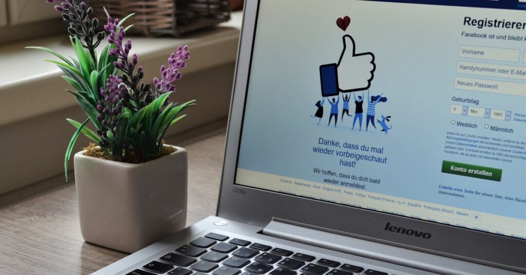 A Lenovo laptop displaying Facebook login beside a lavender plant indoors.